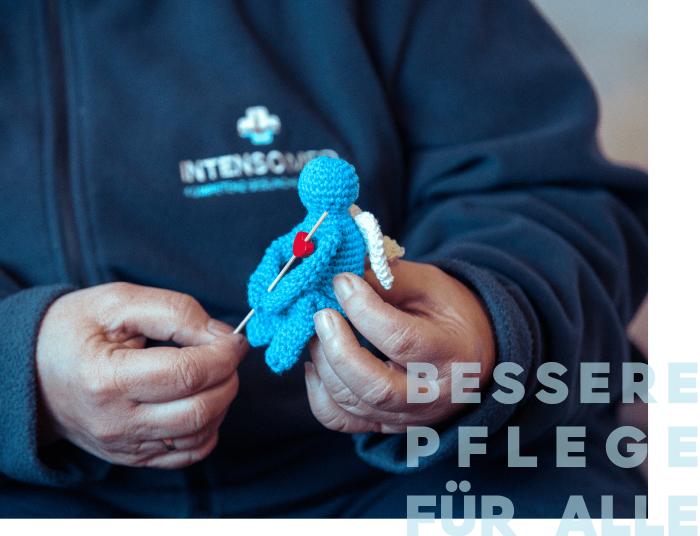 Eine Person hält eine gehäkelte, blaue Figur mit einem Herzen.