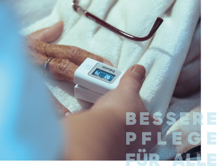 Eine Hand mit einem Pulsoximeter misst den Sauerstoffgehalt einer anderen Hand, die auf einer weichen Decke liegt.