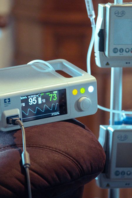 Ein medizinisches Überwachungsgerät zeigt Vitalzeichen auf einem Bildschirm, während es an einen Patienten angeschlossen ist.