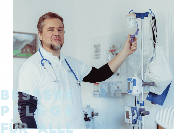 Ein Mann in einem weißen Hemd mit Stethoskop hält eine Infusionstropfstation.