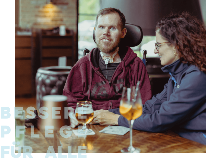Ein Mann mit Tracheostoma und eine Frau sitzen in einem modernen Café.